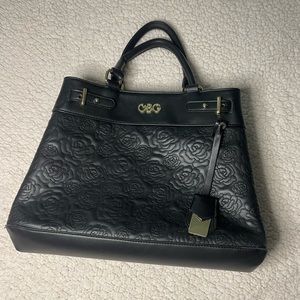 Tote featuring a debossed rose print magnetic closure and a interior zip pocket